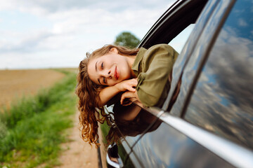 Pretty woman resting and enjoying travel out of the car window. Lifestyle, weekend, tourism,...