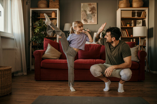 Dad and daughter enjoy exercising together in their bright, spacious living room