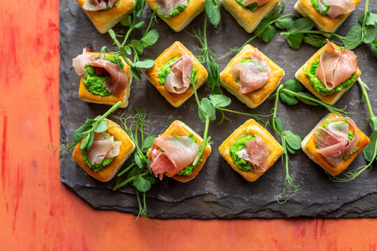 Puff pastry bites with Parma ham, pea puree, and pea shoots