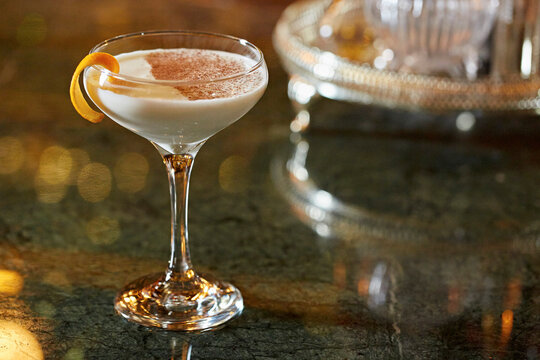 A white cocktail, garnished with orange and chocolate