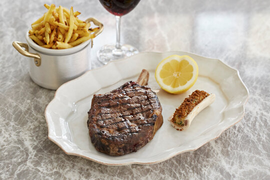 Steak and chips with breaded marrow in the bone and a glass of red wine