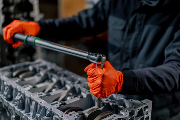 close-up At a service station in the hands of a master a device for tightening bolts works with bolts on the engine