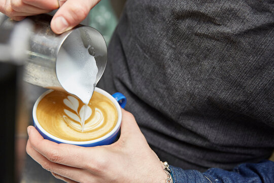 Naklejki Latte art being poured on a coffee