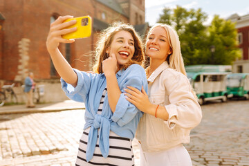 Happy women taking selfie while walking down the street. Fashion, travel, technology, blogging...