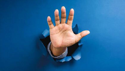 Open male hand breaks through a blue wall. Concept of breaking, changing, shock, marketing message