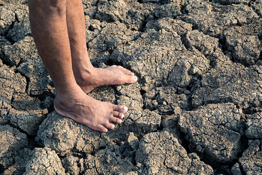 A farmer's bare feet on dry and cracked soil. drought, global warming
