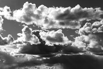 Cloudy sky on a changeable day. High contrast dramatic background in black and white with emotional...