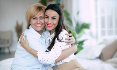 Close up image of happy serene beautiful daughter and smiling middle aged lovely mother hugging each other and looking on camera. Great mother's day or family day. Love emotions from mom and kid