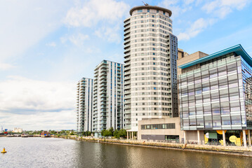 Modern residential towers by beside a glass office building in a quayside redevelopment on a partly cloudy summer day