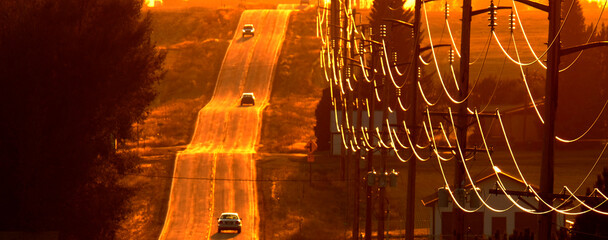 Cars Driving on County Road at Sunset or Sunrise