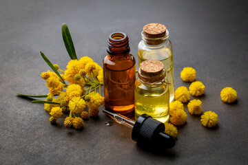 Mimosa essential oil in a glass bottle. Natural cosmetics, aromatherapy and spa concept