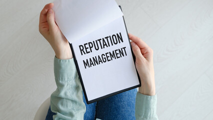 REPUTATION MANAGEMENT text written on notebook on grey background with chart in hands, business...