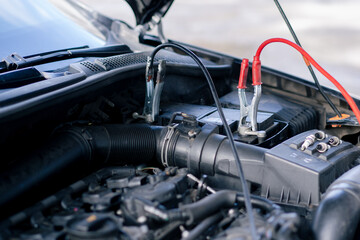 close-up At a service station a battery in a car with tongs connected for charging the battery