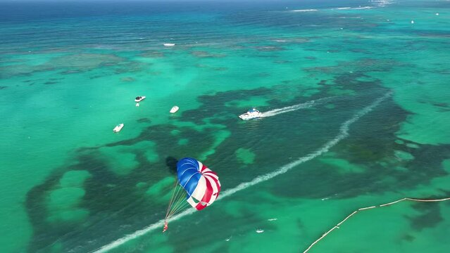 Aerial view of parasailing. Fun water sports. Adrenaline. Parachute high in the sky. Caribbean Sea showcasing boats and various water activities enjoyed by tourists, stunning turquoise waters