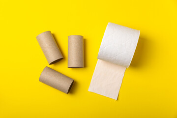 Empty toilet paper roll. Empty rolls and a new roll of toilet paper for the toilet, on a bright yellow background. Paper tube of toilet paper. Place for text. Copy space. Flat lay. Eco-friendly reuse 
