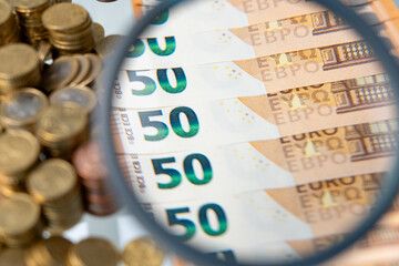 Close up of magnifying glass enlarging the view of some new fifty euro banknotes in a row with...