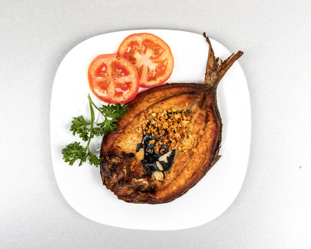 Top down view of fried Filipino milk fish, or Daing na Bangus, breakfast on a white plate