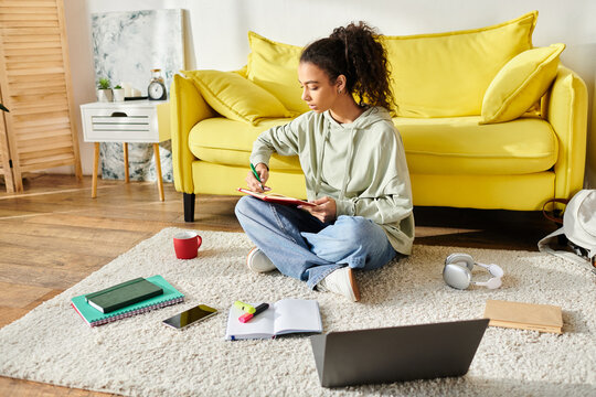 A teenage girl engrossed in e-learning, sits on the floor with a laptop.