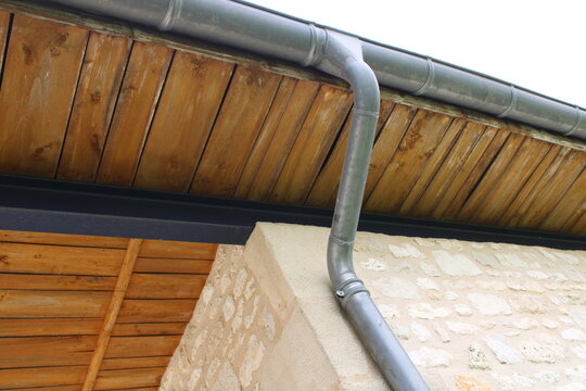 Gouttière zinc gris sur la façade de la maison, descentes rondes et  sous-face en lambris bois