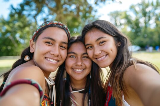 Three smiling Native American friends taking a selfie in a park