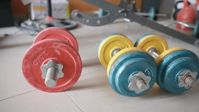 Orbit motion close up of the colored heavy adjustable dumbbell set lying on the floor in the living room. Home gym equipment