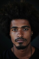 Fototapeta premium Close-up photo of a young man showcasing his natural curly afro hair against a dark background