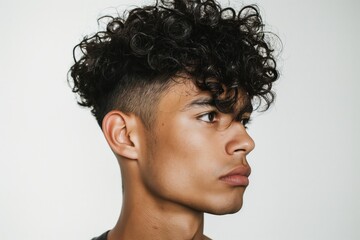 Side profile of a trendy curly undercut hairstyle on a young adult male against a white background
