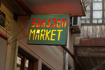 Street photo. Horizontal green sign for grocery store, supermarket, shop with glowing red and...