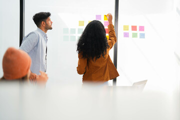 Team leader engages with colleagues on project details, utilizing a transparent board for agile...
