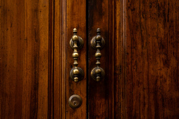 Old brown wooden door with antique handles, detail of a door. Metal knocker on a door