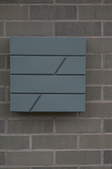 a gray mailbox hangs on a gray brick wall