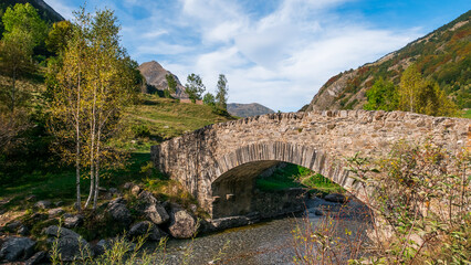 Fototapeta na wymiar Gavarnie, Hautes-Pyrénées, France - October 13, 2023: Medieval stone bridge over the Gave de Gavarnie river
