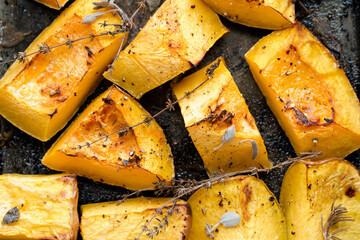 Pieces of organic oven roasted butternut squash in a baking sheet pan with fresh thyme and sage...