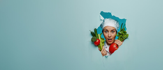 Surprised chef in uniform emerges from a green torn paper background holding fresh vegetables, symbolizing healthy eating