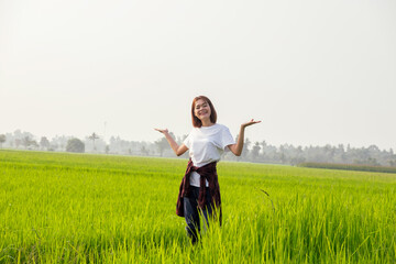 A joyful woman jumps with open arms in a green field under a blue sky, embodying freedom and...