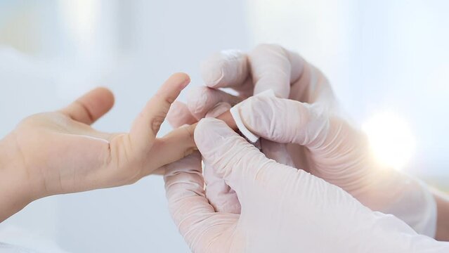 Finger prick blood test performed by doctor on child patient in clinic.