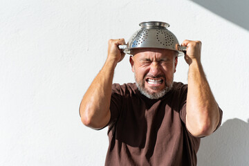 bearded cheerful man with a colander on his head. cheerful portraits of a man with a colander - obrazy, fototapety, plakaty