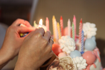 Female hands lighting candles on a birthday cake. The warmth and joy of a birthday celebration