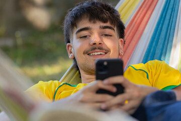 young male in hammock with mobile phone - 781485585