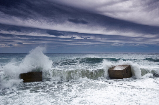 Stormy weather and a concrete structure coastline barrier with the sea beyond