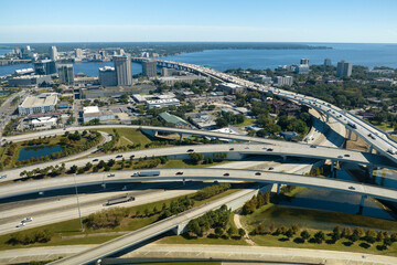 Aerial view of Jacksonville city with high office buildings and american freeway intersection with fast moving cars and trucks. USA transportation infrastructure concept