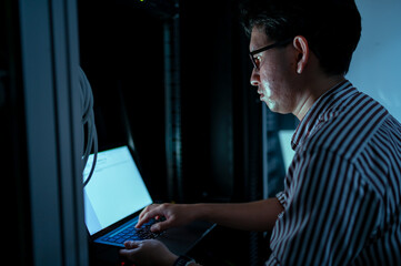 Computer engineer is setting up network in server room,Systems Maintenance Technician,Male engineer working in server room at modern data center