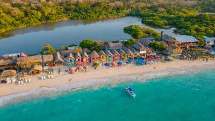 Aerial view of Playa Blanca, Baru, with crystal clear waters, white sandy beach, colorful huts, and lush greenery