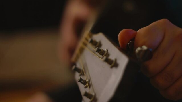 Close up tunning an acoustic guitar