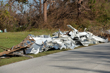 Piles of rubbish on street side from severely damaged houses after hurricane in Florida mobile home...