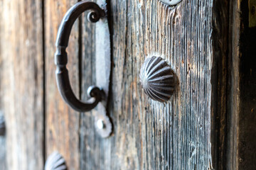 A wooden door with a metal handle and a decorative knob. The knob is shaped like a shell and has a...