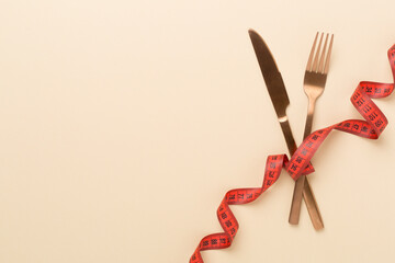 Measuring tape with fork and knife on color background, top, view.Weight loss concept