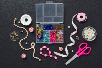 Tools and beads for making handmade jewelry on concrete background, top view