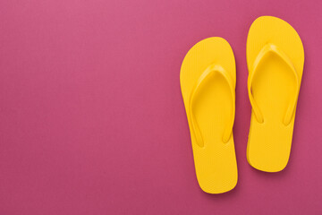 Bright yellow flip-flops on color background, top view. Summer concept