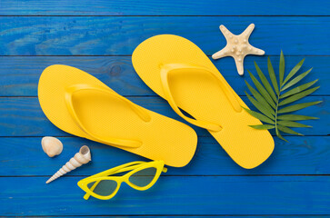 Bright yellow flip-flops on wooden background, top view. Summer concept